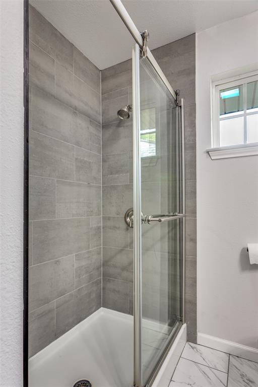 6921 Valhalla Road Fort Worth, TX 76116 - Photo 18 of 25 Full bath featuring a stall shower, light marble finish flooring, and a textured ceiling
