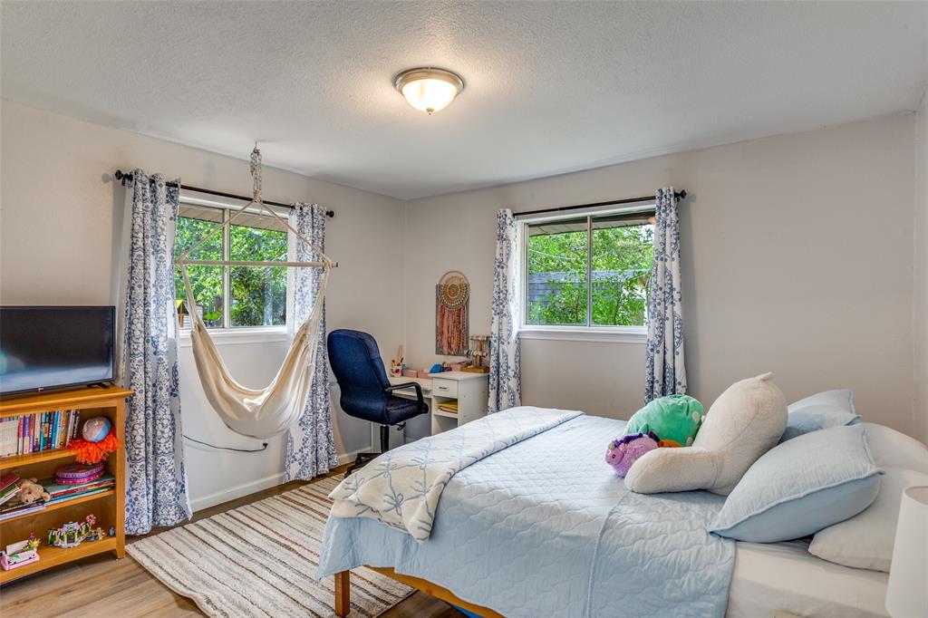 6921 Valhalla Road Fort Worth, TX 76116 - Photo 21 of 25 Bedroom with multiple windows, wood finished floors, and a textured ceiling