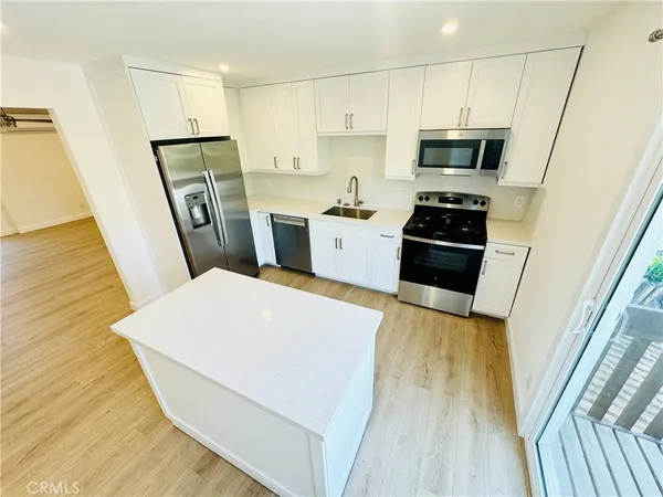 a kitchen with a refrigerator a stove top oven a sink and dishwasher with wooden floor