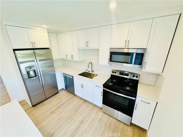 a kitchen with a sink a refrigerator a microwave and cabinets