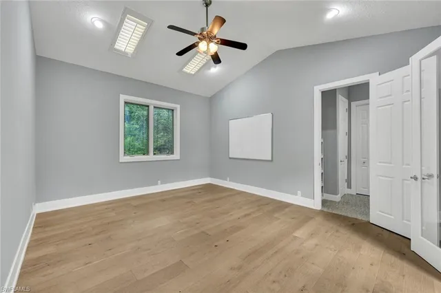 an empty room with ceiling fan and windows