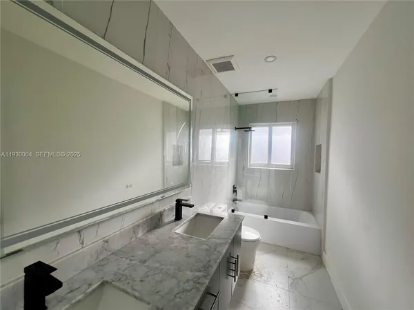 a bathroom with a granite countertop sink a toilet and bathtub