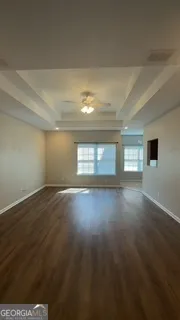 a view of empty room with wooden floor and fan