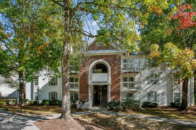 a front view of a house with large trees