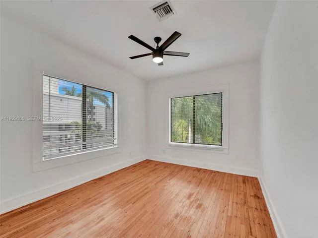 a view of empty room with wooden floor and fan