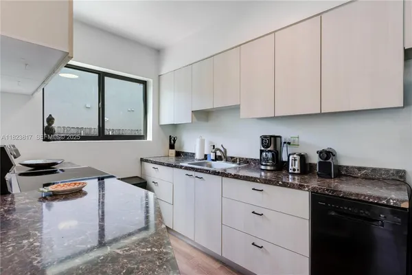 a kitchen with granite countertop a sink a stove and cabinets