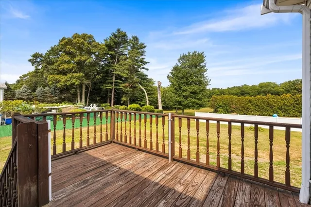 a balcony with wooden floor next to a yard