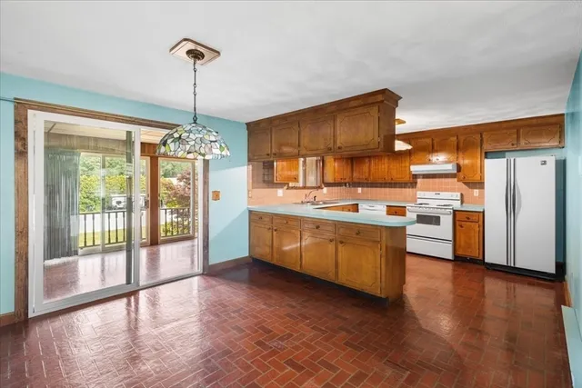 a kitchen with stainless steel appliances granite countertop a refrigerator a sink dishwasher a stove and a dining table with wooden floor