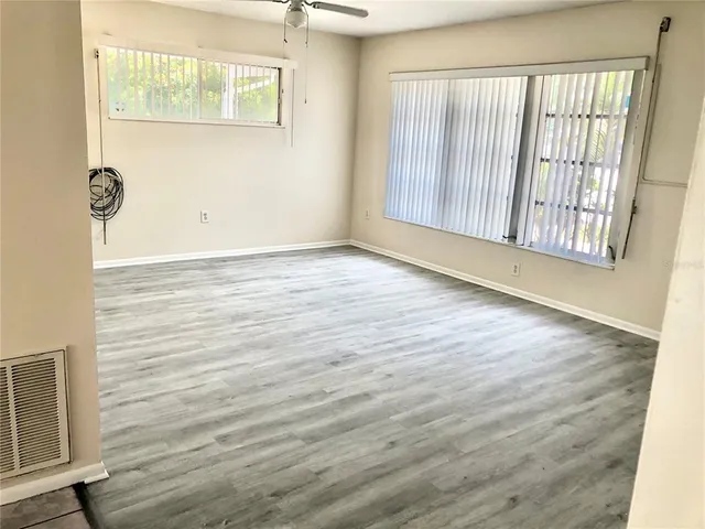 an empty room with wooden floor and windows