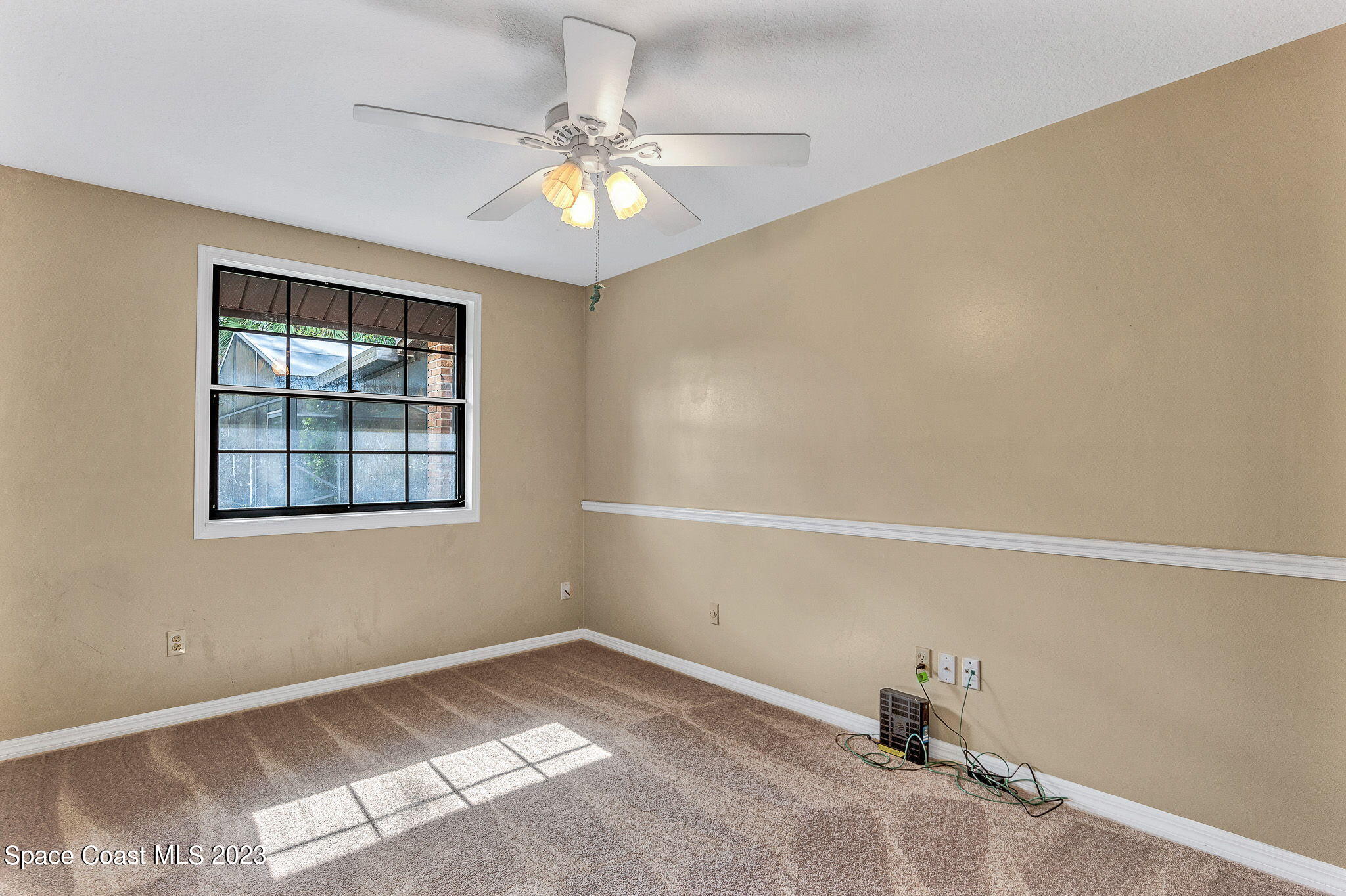 2281 Friday Road Cocoa, FL 32926 - Photo 14 of 72 an empty room with a chandelier fan and windows