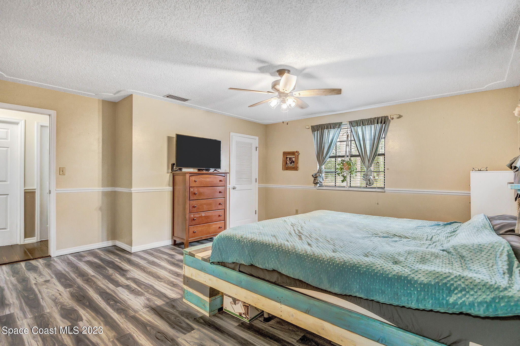 2281 Friday Road Cocoa, FL 32926 - Photo 8 of 72 a bedroom with a large bed a flat tv screen and a chandelier