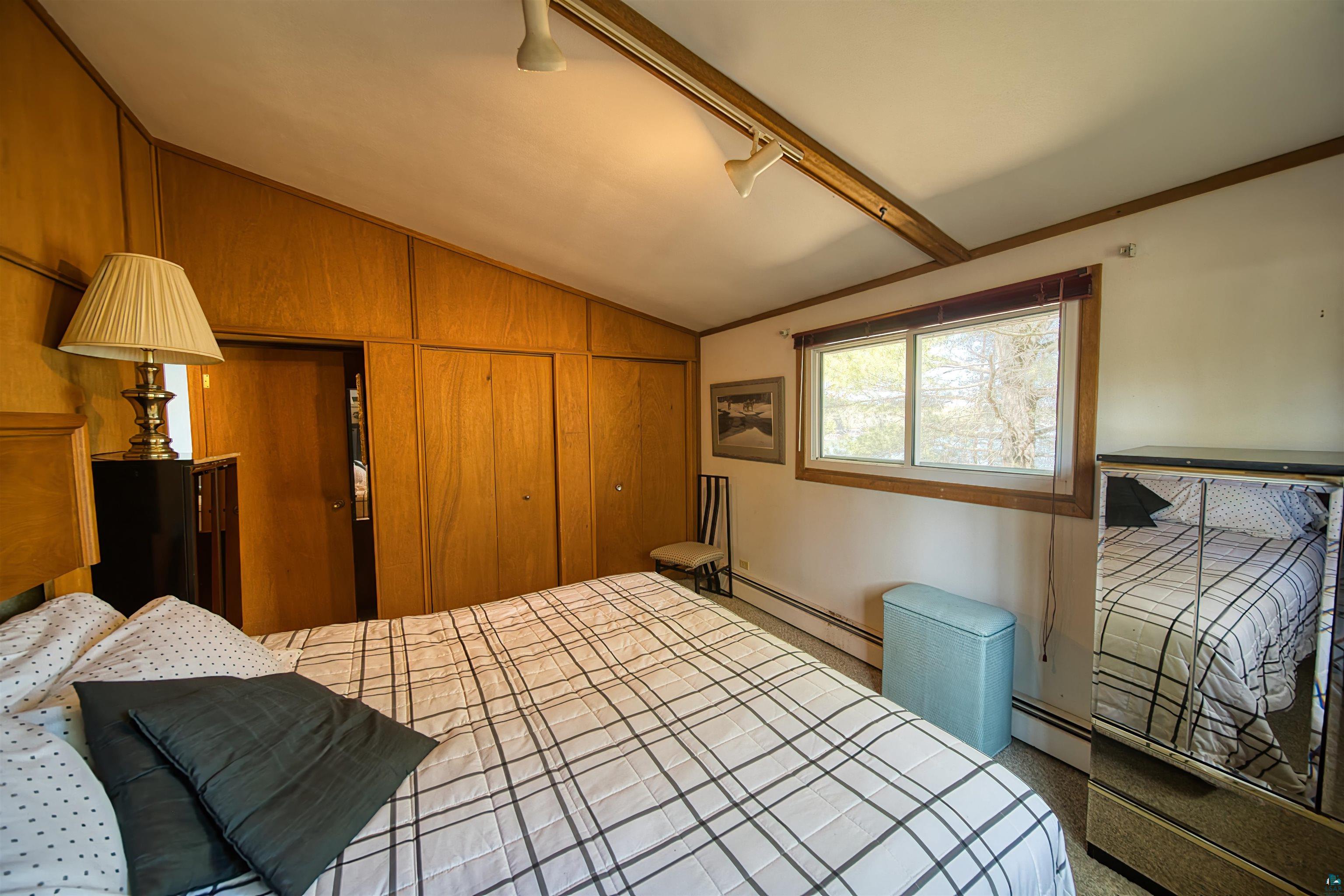 29836 Long Lake Road Danbury, WI 54830 - Photo 18 of 40 Bedroom with a baseboard heating unit, vaulted ceiling, a closet, and wood walls