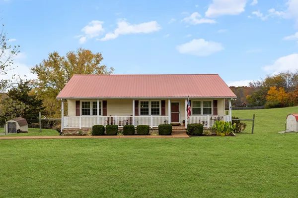a front view of a house with a garden and trees