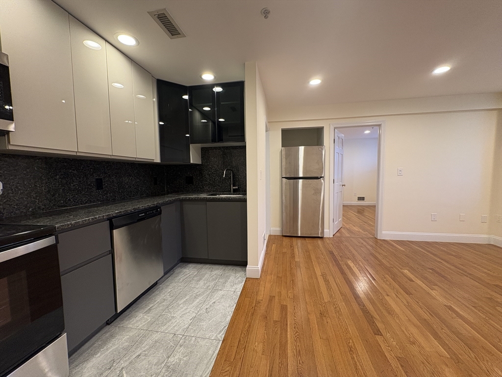 1801 Beacon Street, Unit 1 Brookline, MA 02445 - Photo 2 of 14 a kitchen with granite countertop kitchen island wooden floors and stainless steel appliances