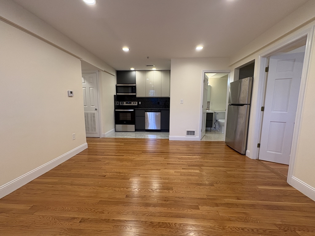 1801 Beacon Street, Unit 1 Brookline, MA 02445 - Photo 3 of 14 a view of kitchen and empty room with wooden floor