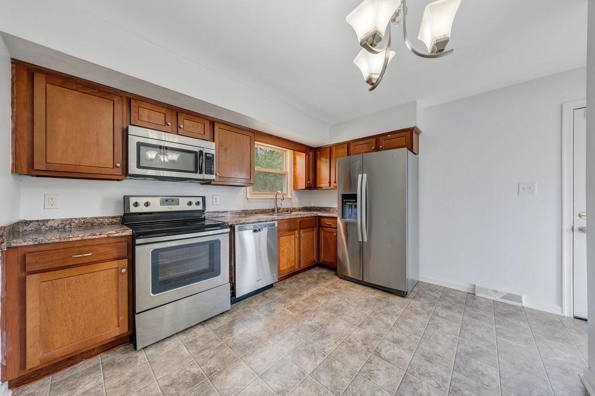 756 Kenyon Road Vinton, VA 24179 - Photo 9 of 14 a kitchen with stainless steel appliances granite countertop a refrigerator a stove a sink dishwasher a dining table and chairs with wooden floor