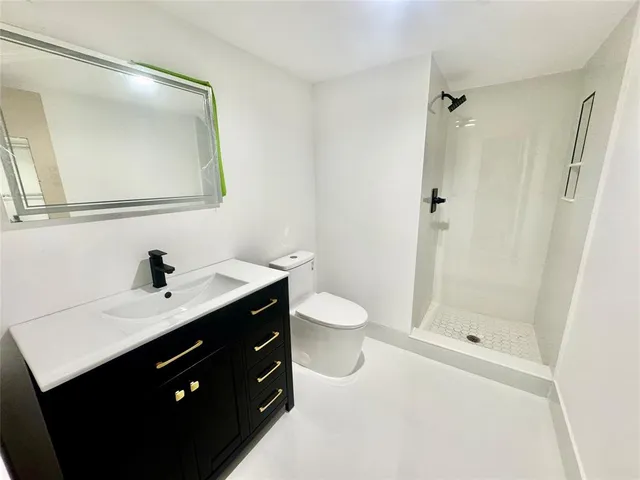 a bathroom with a sink a toilet a mirror and shower