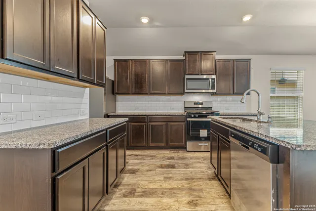 a kitchen with kitchen island granite countertop a stove sink and microwave