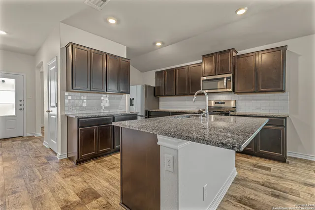 a large kitchen with stainless steel appliances granite countertop a stove a sink and a microwave