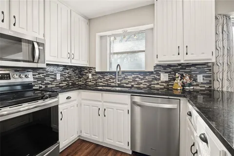 a kitchen with stainless steel appliances granite countertop a sink dishwasher a stove and a microwave oven with cabinets