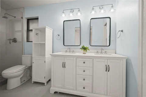 a bathroom with double vanity sink a mirror and a toilet