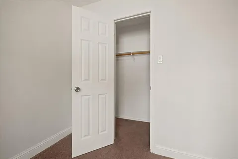 an empty room with chandelier fan and windows