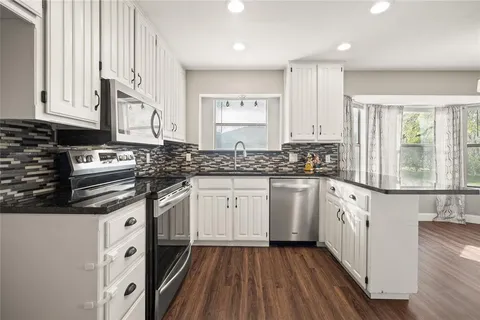 a kitchen with stainless steel appliances granite countertop a stove a sink and white cabinets