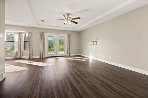a view of an empty room with wooden floor and window