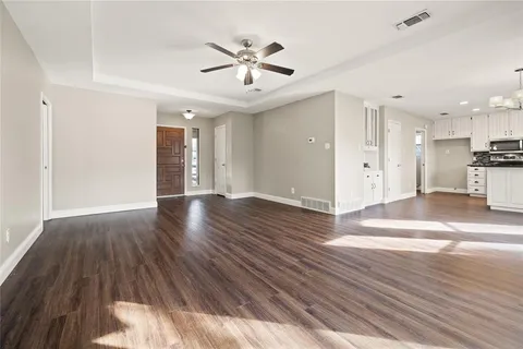 a view of an empty room with wooden floor and a ceiling fan