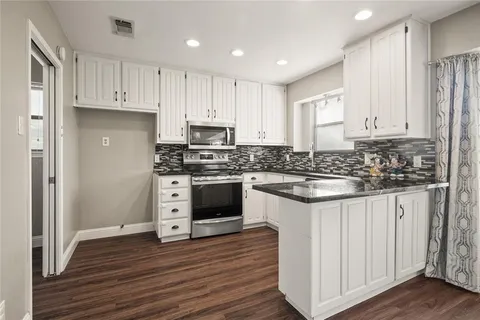 a kitchen with granite countertop white cabinets and white appliances