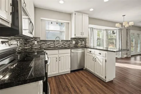 a kitchen with stainless steel appliances a sink stove and wooden floor