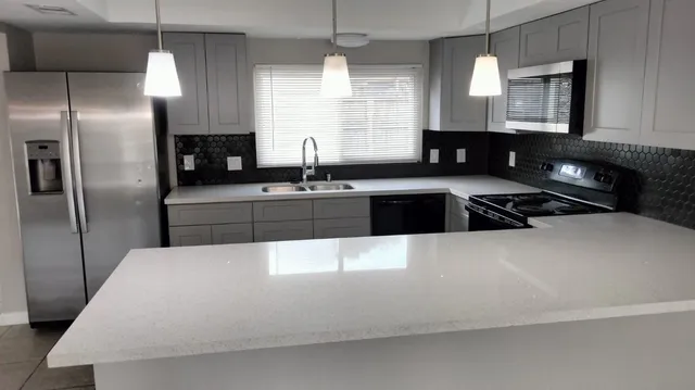 a kitchen with kitchen island granite countertop a sink a counter space appliances and cabinets