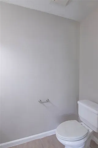 a white toilet sitting next to a white wall