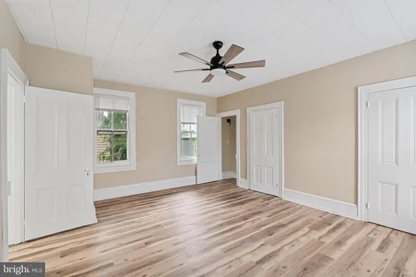a view of empty room with wooden floor and fan