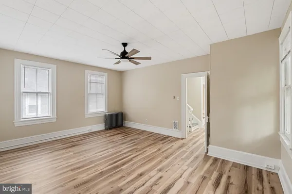 a view of an empty room with window and wooden floor