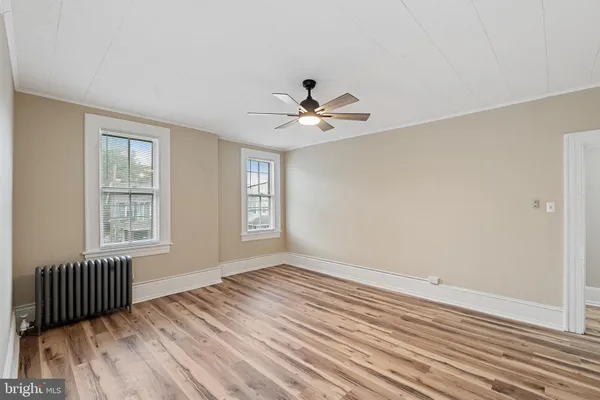 a view of an empty room with a window and wooden floor