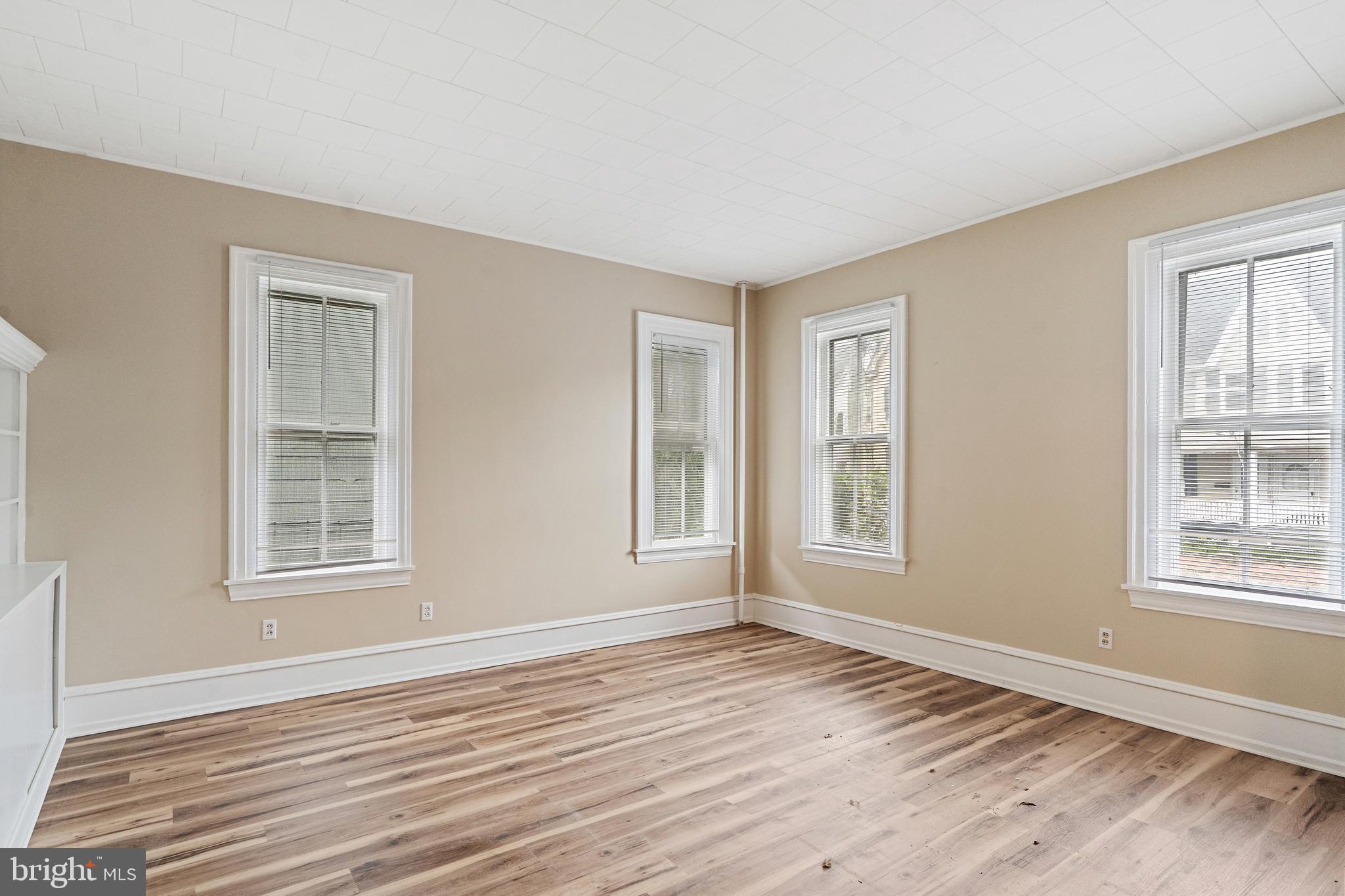 154 7th Street Salem, NJ 08079 - Photo 6 of 48 a view of an empty room with wooden floor and a window