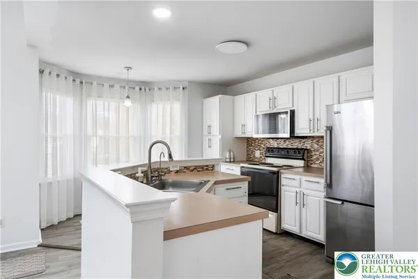 a kitchen with stainless steel appliances granite countertop a refrigerator a sink dishwasher a stove with white cabinets and wooden floor