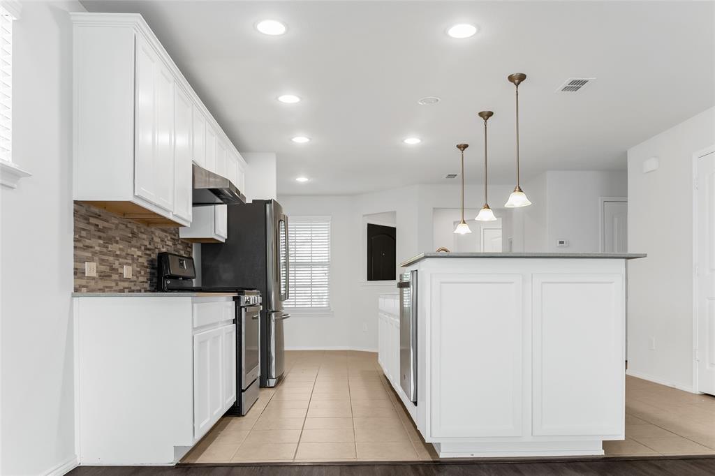 7793 Gulf Walk Road Frisco, TX 75036 - Photo 13 of 37 a kitchen with stainless steel appliances kitchen island granite countertop a refrigerator a oven a sink and white cabinets with wooden floor