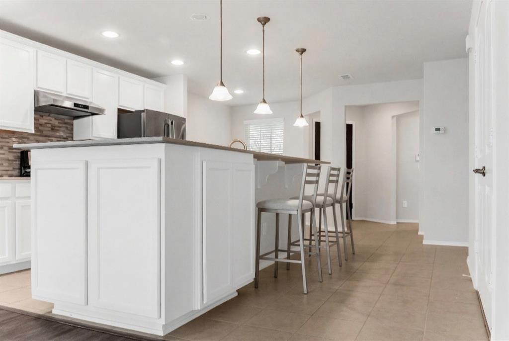 7793 Gulf Walk Road Frisco, TX 75036 - Photo 15 of 37 a large kitchen with kitchen island a dining table chairs sink and wooden floor