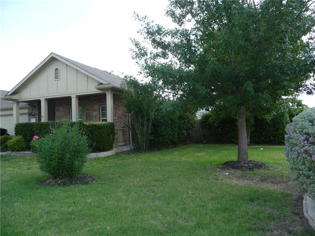 a view of a house with backyard and a tree