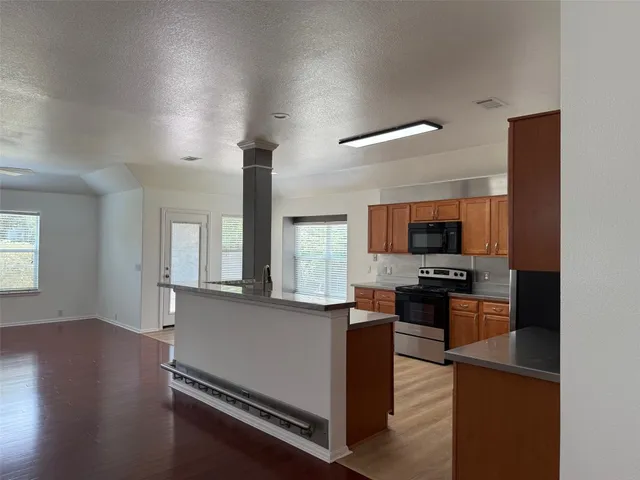a view of a kitchen with kitchen island a sink a counter space and stainless steel appliances