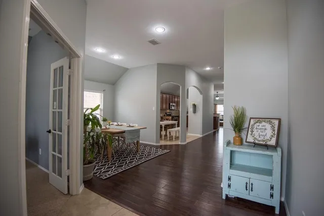 a view of a hallway to room with wooden floor and furniture