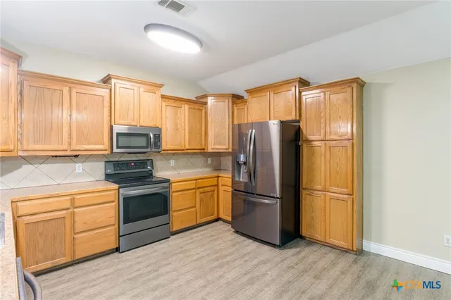 a kitchen with stainless steel appliances granite countertop a refrigerator stove and sink