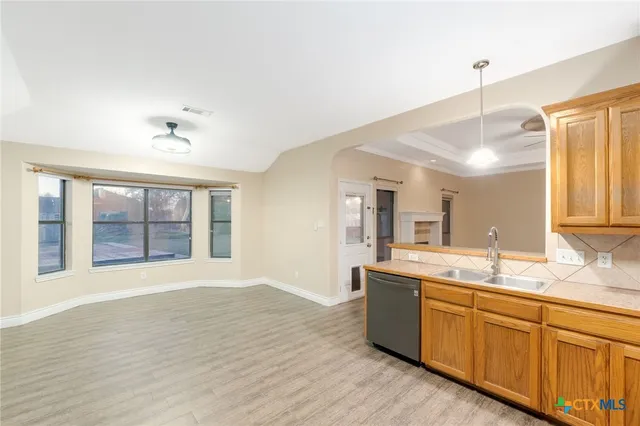 a kitchen with stainless steel appliances granite countertop a sink cabinets and wooden floor