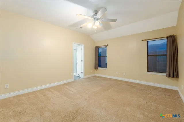 a view of an empty room with chandelier fan