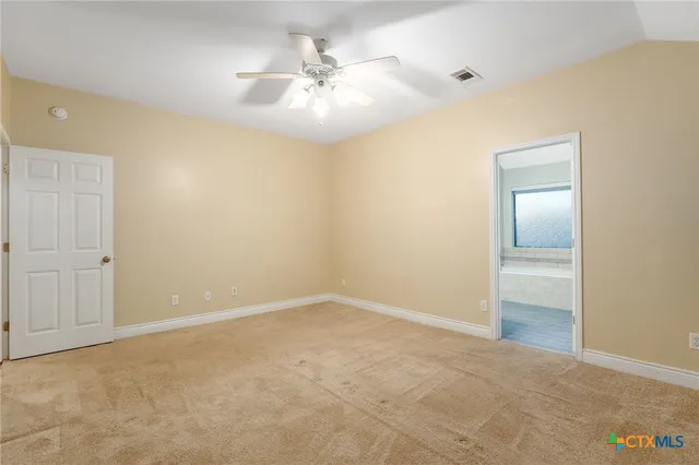 an empty room with a chandelier fan and windows