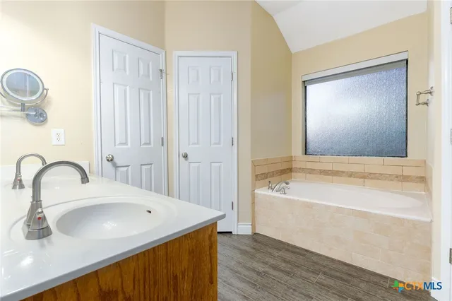 a bathroom with a tub sink and mirror