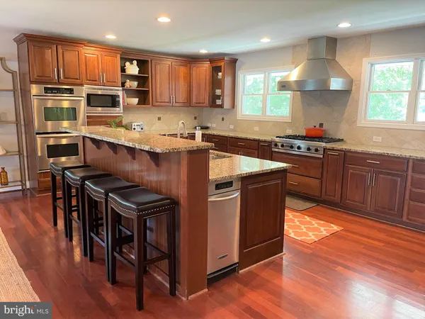 a kitchen with kitchen island granite countertop wooden floors appliances and cabinets
