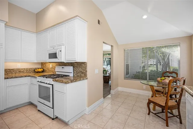 a kitchen with stainless steel appliances a stove a sink refrigerator and a view of living room